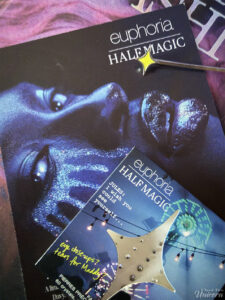 Half Magic Euphoria promotional card, with Face Gems in its packaging, and a Half Magic bobbi pin on top of the Euphoria Fashion book