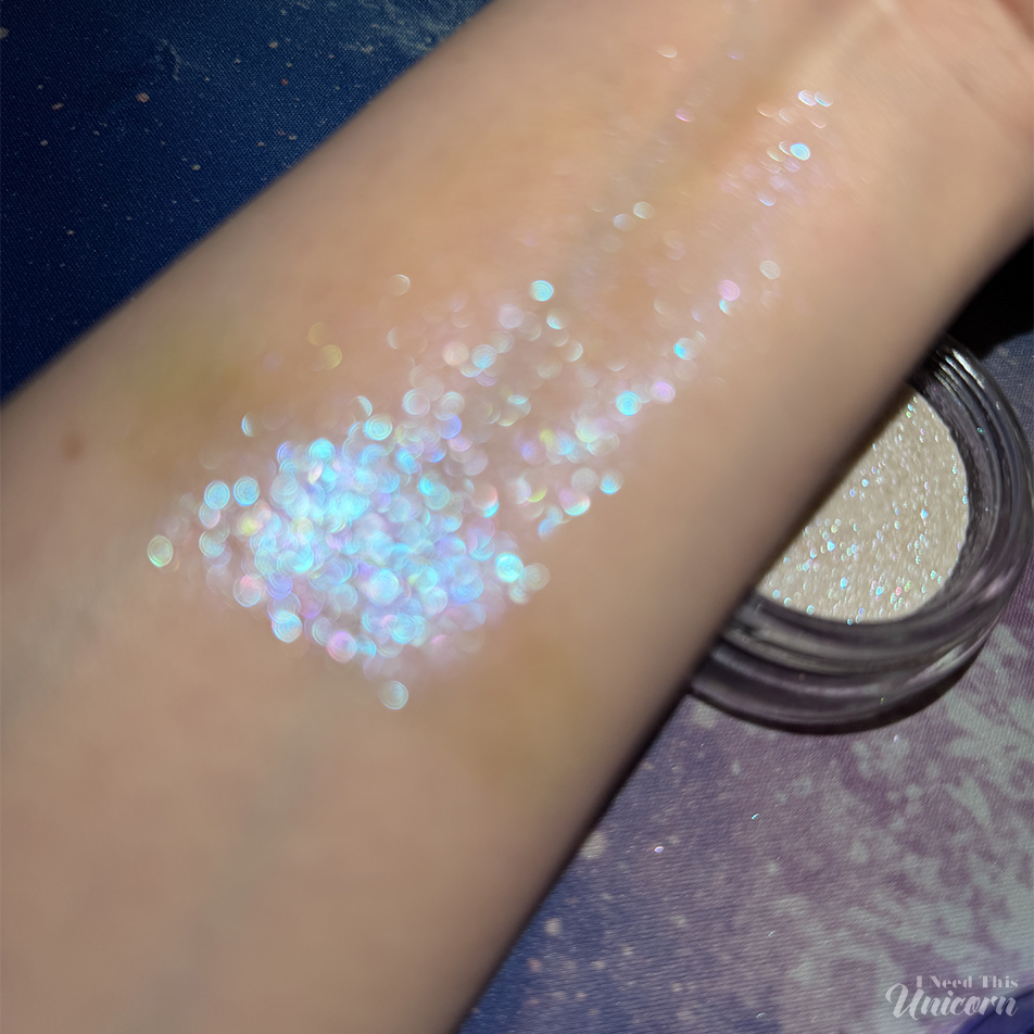 Half Magic Euphoria Glitter Puck in Feel Something swatch on arm, unfocused to show sparkle