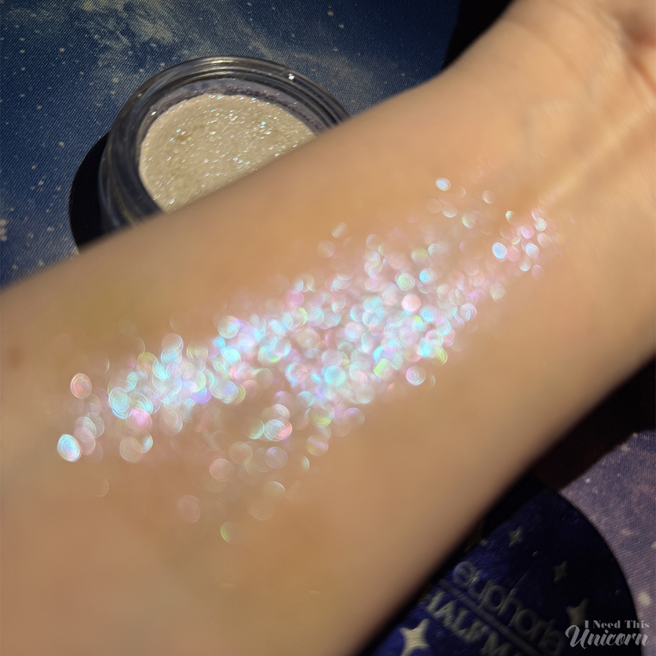 Half Magic Euphoria Glitter Puck in Feel Something swatch on arm, unfocused to show sparkle