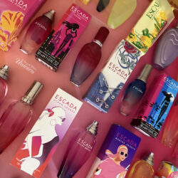 Massive collection of Escada limited edition summer fragrances with their boxes, all lined up on a pink to orange ombre wrapping paper background