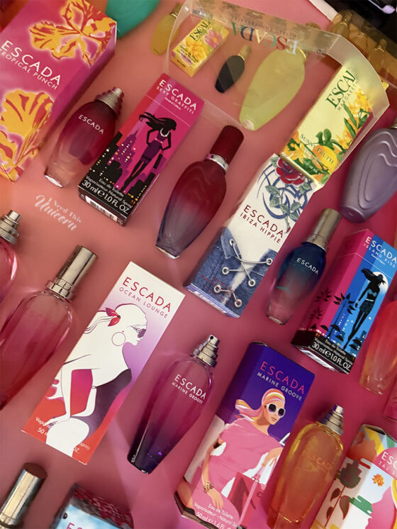 Massive collection of Escada limited edition summer fragrances with their boxes, all lined up on a pink to orange ombre wrapping paper background