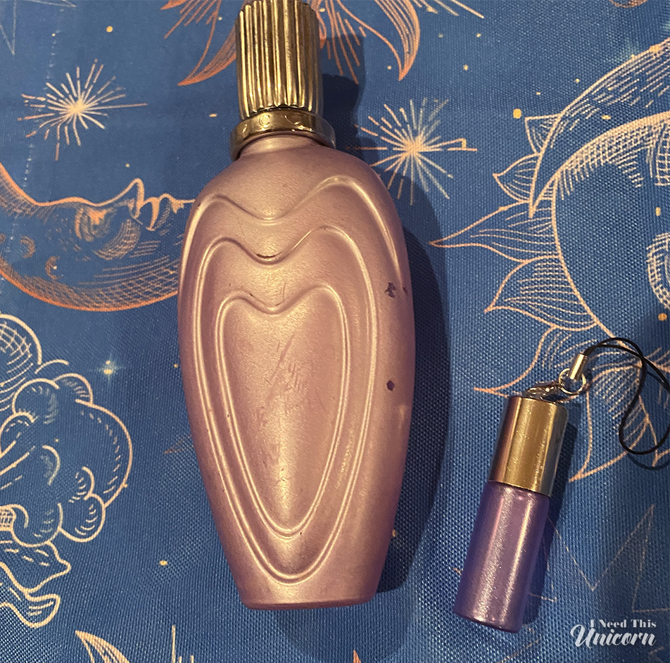 Pearlized lavender bottle of Escada's Loving Bouquet fragrance with a mini travel size atomizer, given to me as a fun freebie by the EBay seller, on a celestial tablecloth background.