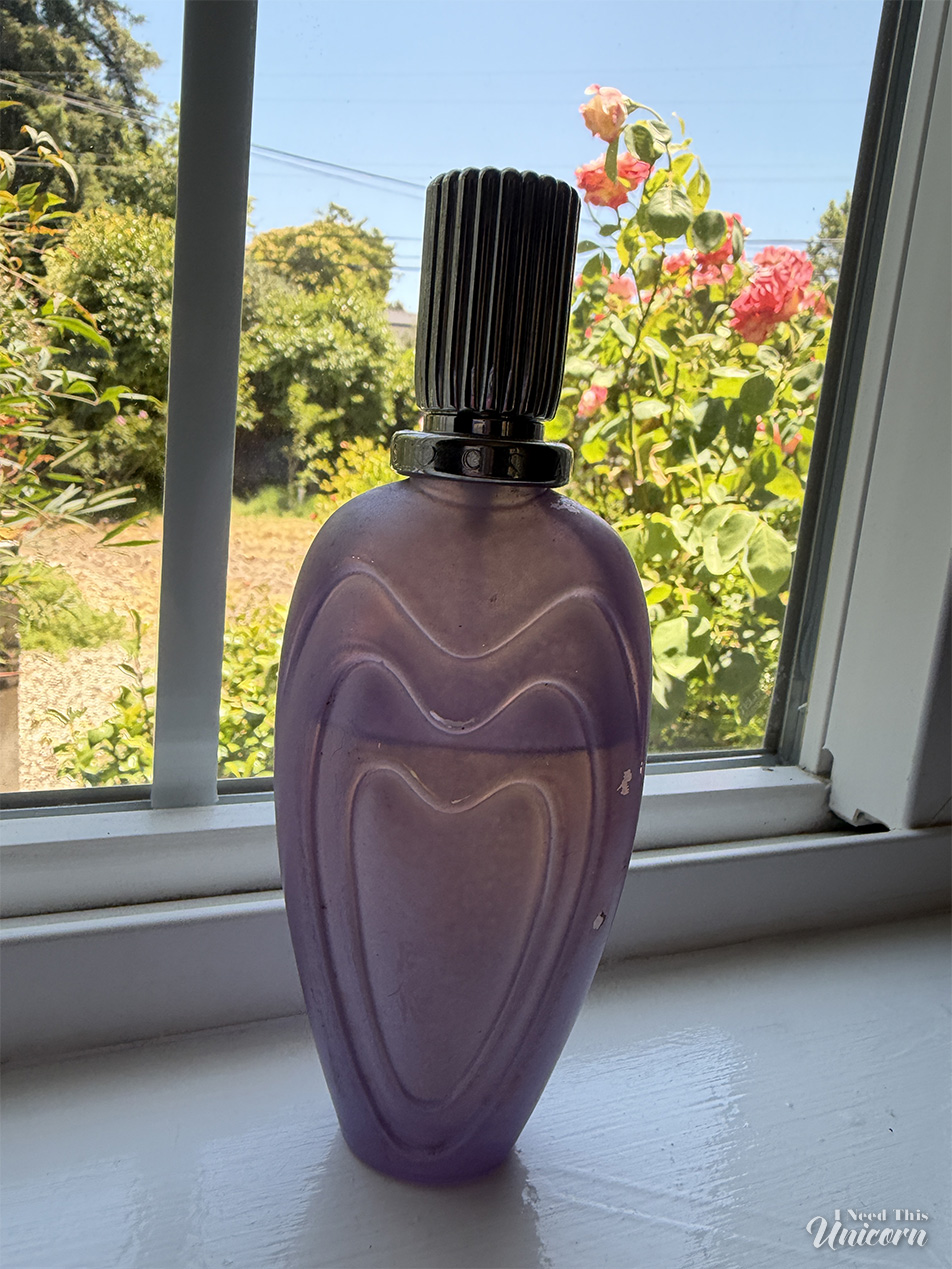 Lavender colored bottle of Escada's Loving Bouquet fragrance on a window sill