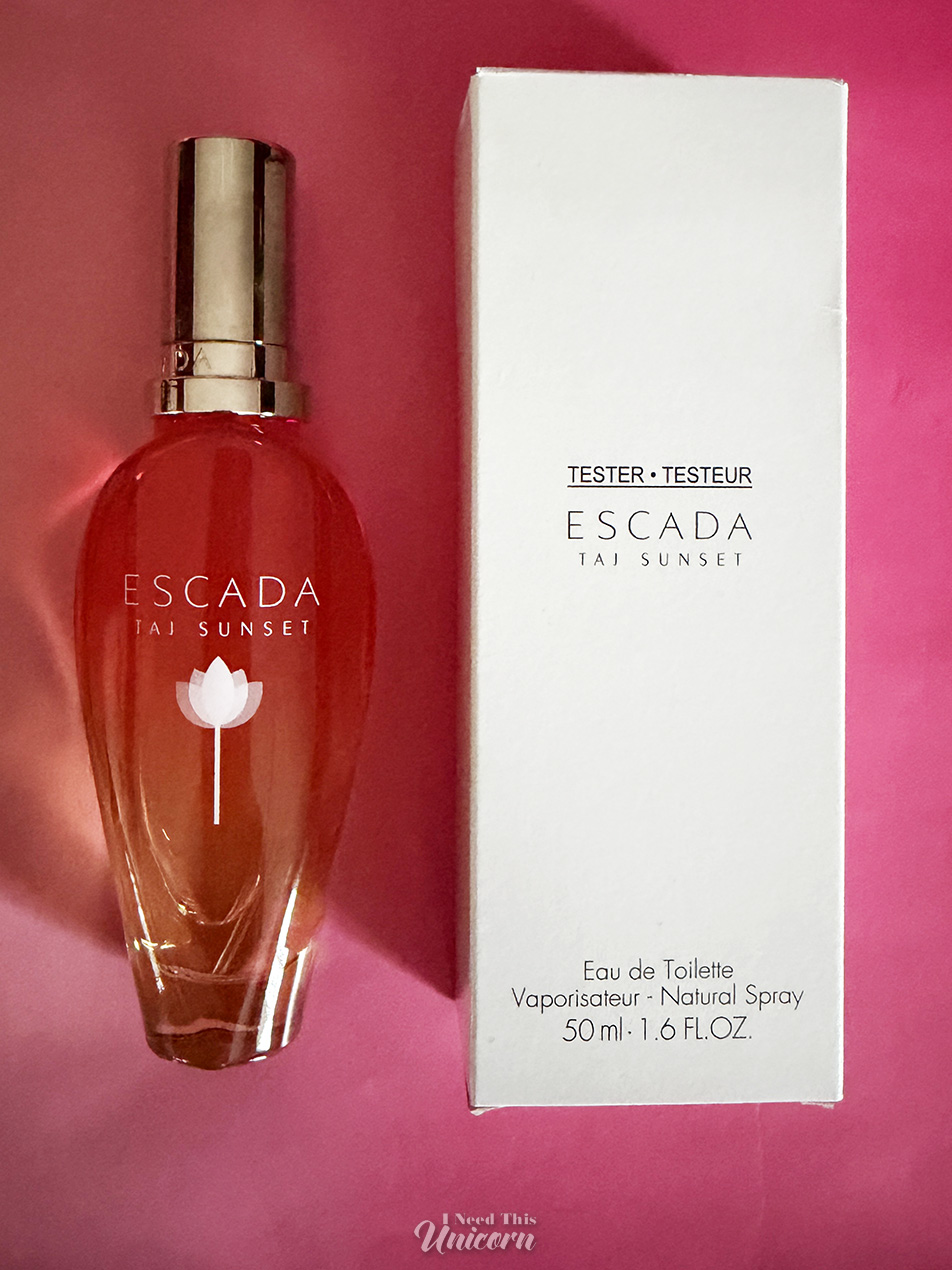 Bottle of the new repromoted Taj Sunset from 2025, with the blank "tester" box it came with, on a pink background.