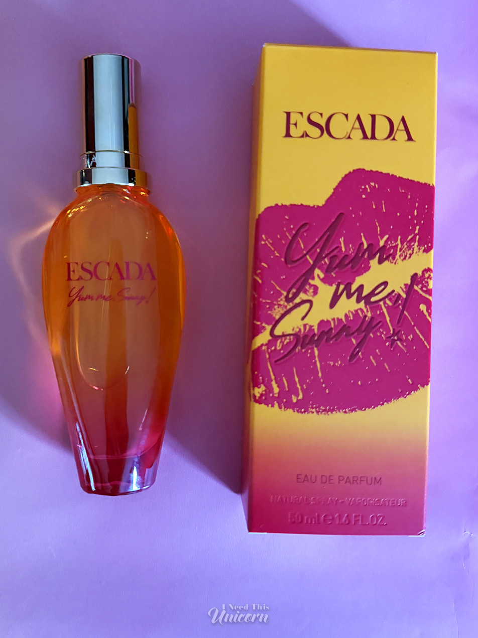 Orange to magenta gradient bottle of Yum, Me Sunny! and it's box on a pink background