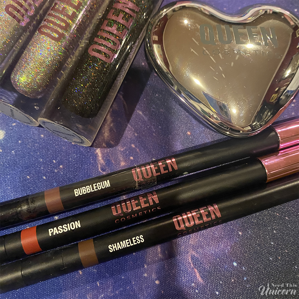 Queen Cosmetics Bubblegum, Passion, and Shameless lip liners displayed alongside holographic lip glosses and a heart-shaped compact. The nude brown, bright red, and deep brown liners were included as free gifts with a Queen Cosmetics TikTok Shop order.