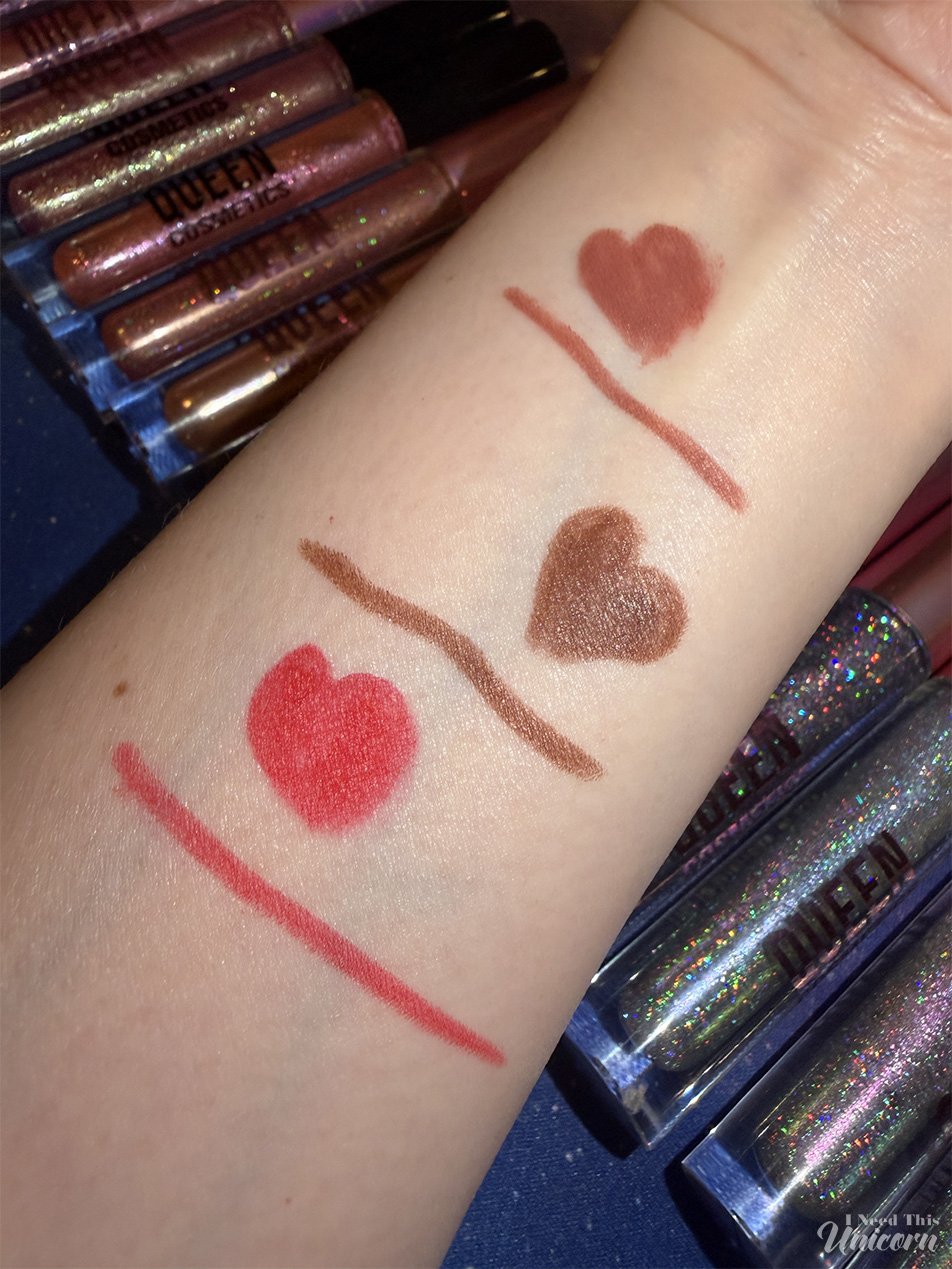 Swatches of Queen Cosmetics lip liners Bubblegum, Shameless, and Passion on fair skin. Bubblegum is a nude pink-brown, Shameless is a medium brown, and Passion is a vibrant red-orange. Heart-shaped swatches show the full liner color payoff.