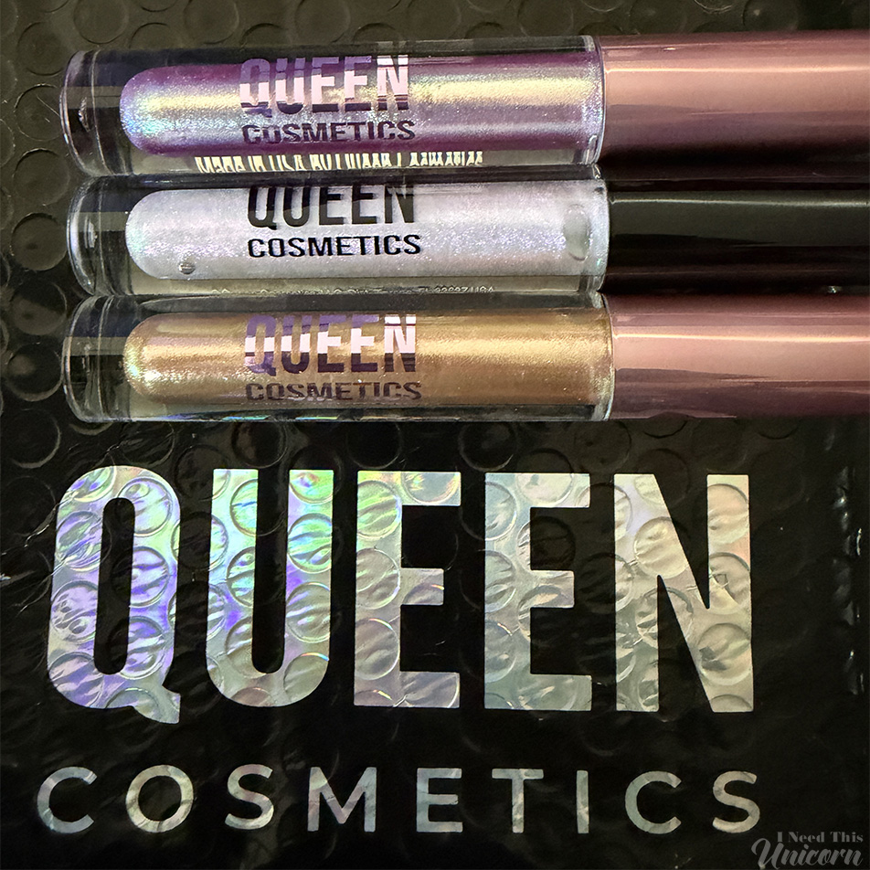 Queen Cosmetics Tester Diamond Shimmer Glosses | I Need This Unicorn Closeup of the Queen Cosmetics tester lip glosses on top the the branded mailer with the holographic logo