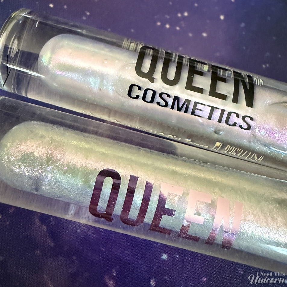 Side-by-side comparison of Queen Cosmetics Tester #2 and Nebula lip glosses in their tubes. Both feature a milky translucent base with pink, blue, lavender, and green iridescence, highlighting their similar appearance in packaging.