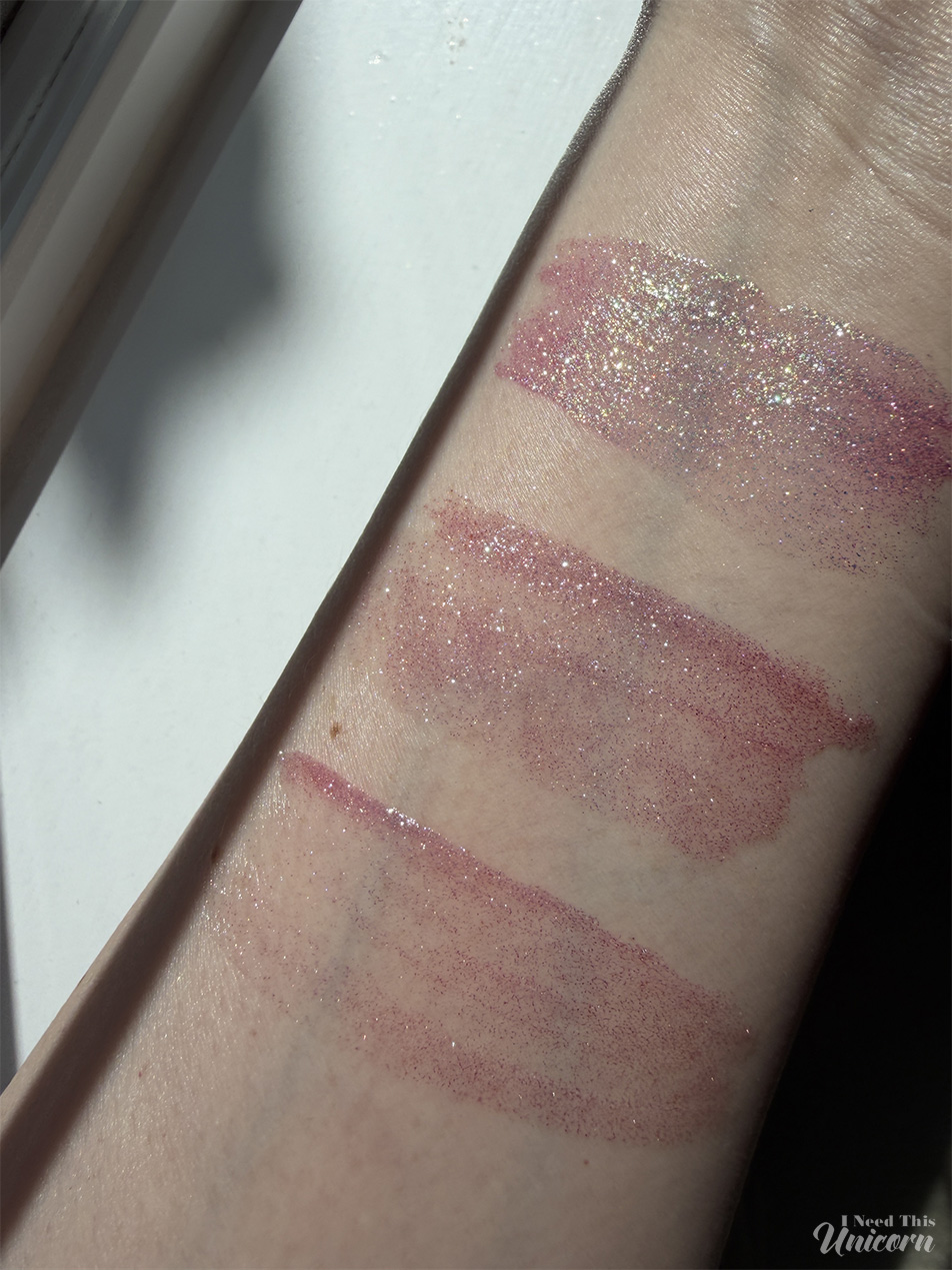 Queen Cosmetics Tester Diamond Shimmer Glosses | I Need This Unicorn Sunlight swatches of Queen Cosmetics Tester #1 (top) and two Moonstone glosses (middle and bottom), highlighting differences in sparkle density, pink tones, and reflective shimmer.