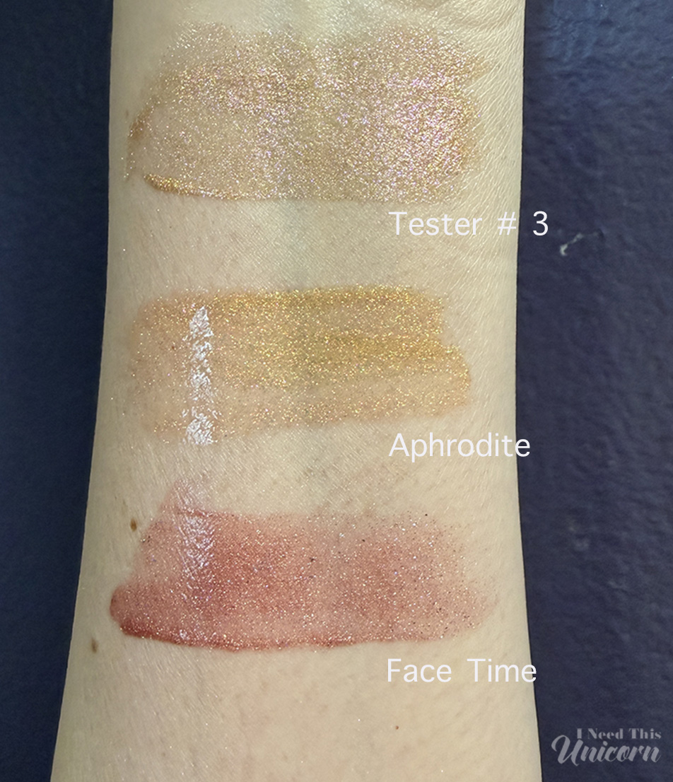 Queen Cosmetics Tester Diamond Shimmer Glosses | I Need This Unicorn Comparison of Queen Cosmetics Tester #3, Aphrodite, and Face Time lip glosses swatched on bare skin. Tester #3 shows a warm champagne-gold shimmer with pink undertones, Aphrodite displays a bright yellow-gold metallic sparkle, and Face Time appears as a rosy nude gloss with fine gold shimmer.