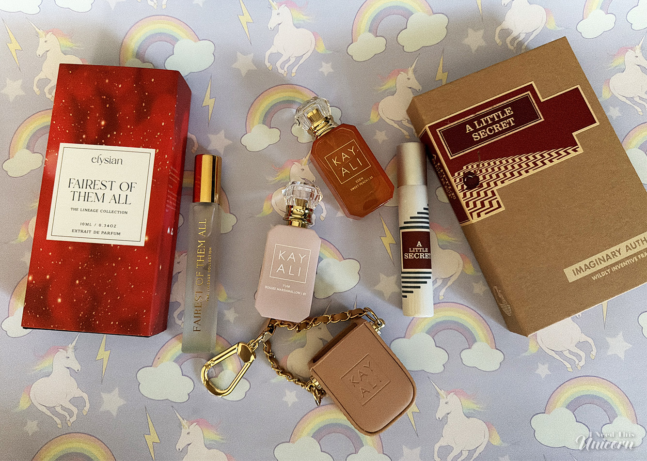 Four travel-size perfumes on a rainbows & unicorns background.