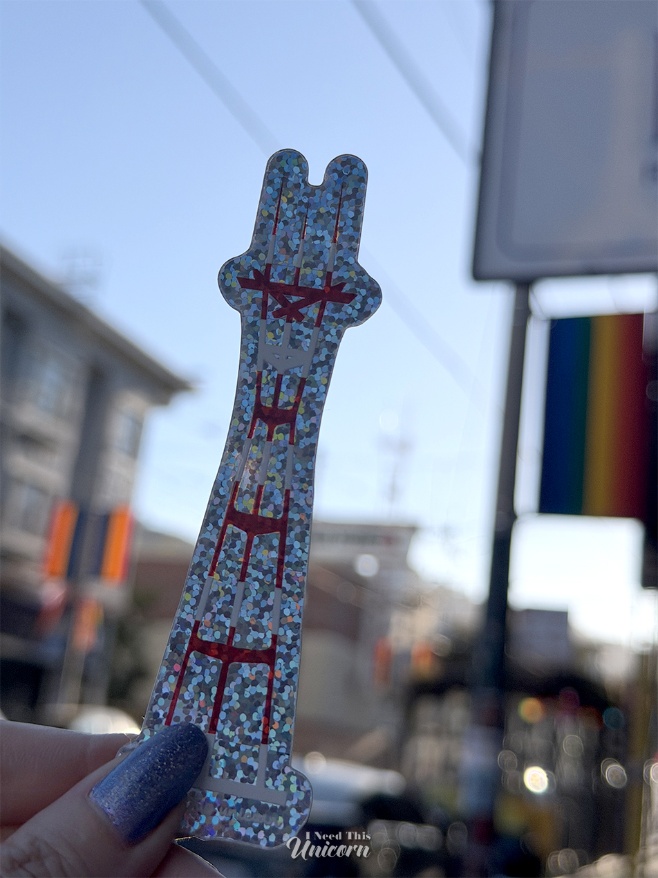 Holographic Sutro Tower sticker being held next to the real deal